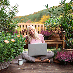 Woman setting in garden using laptop